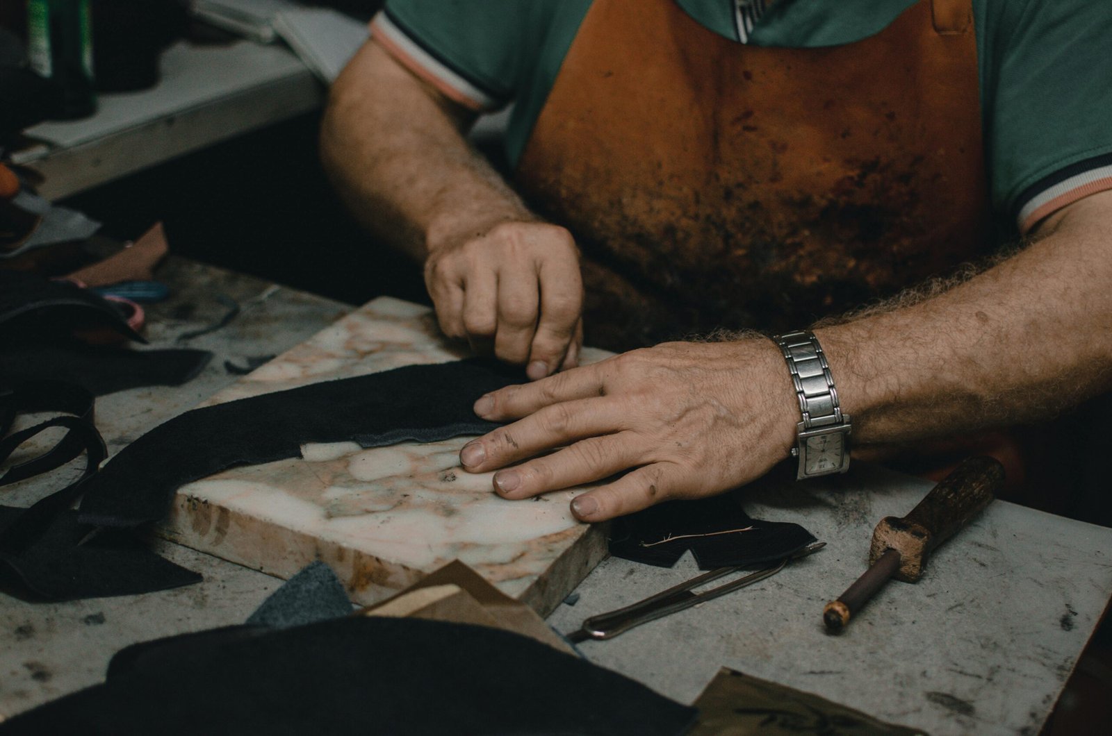 Skilled artisan handcrafting leather pieces on a workstation with precision tools.